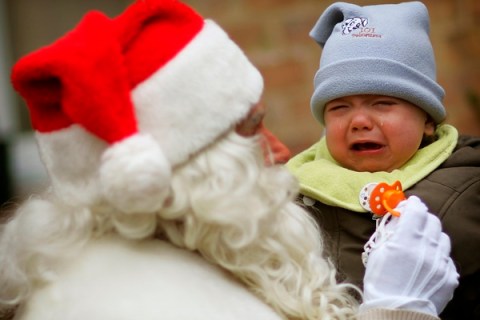 A young child cries after a man dressed as Father Christmas removes its dummy during a photocall in front of a special Christmas post office in the village of Himmelpfort