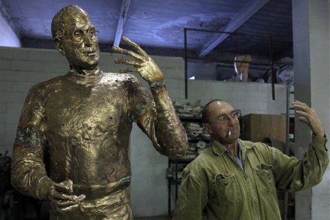 Assistant to Hungarian sculptor Erno Toth mimics the pose of the sculptor's latest work, a bronze statue of late Apple co-founder Steve Jobs, in Budapest