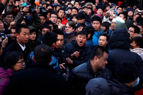 A man yells at a security guard after the guard tried to remove a member of the crowd at the Apple store in the Beijing district of Sanlitun