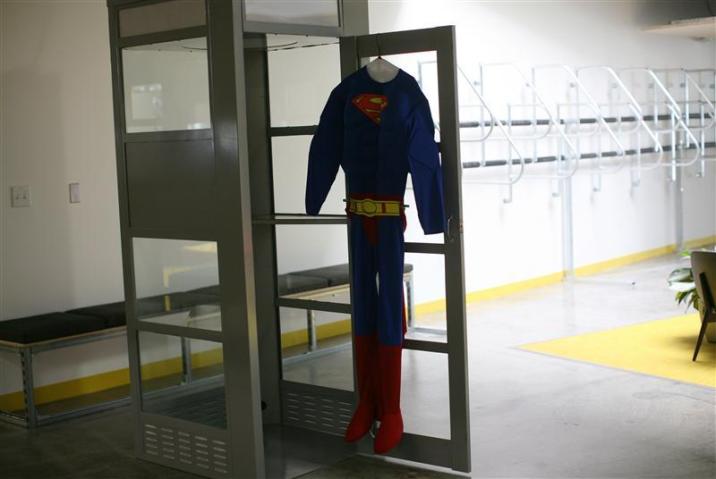 A superman costume hangs at a telephone booth for private cell phone discussions