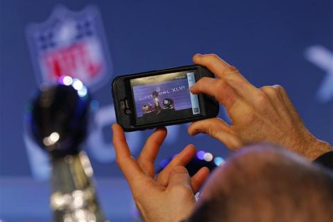 A member of the media takes a cell phone picture of the Vince Lombardi Trophy at a press conference before the Super Bowl XLVI NFL football game in Indianapolis