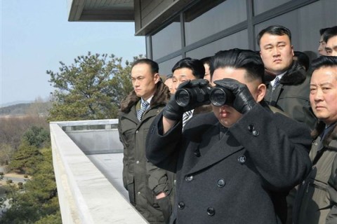 North Korean leader Kim Jong-un looks at South Korea through binoculars as he visits the truce village of Panmunjom