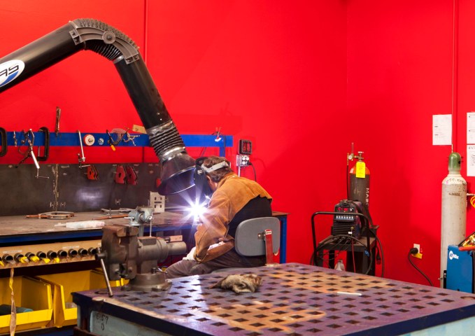 A man welds in the Google Workshops where Googlers recreationally explore hobbies such as machine making and woodworking.